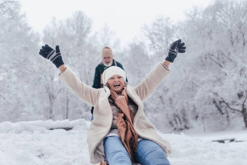 Senior couple having fun during cold winter day, sledding down the hill. Senior woman on sled. Elderly couple spending winter vacation in the mountains. Wintry landscape. - HPIF34501