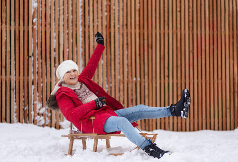 Senior woman having fun during cold winter day, sledding down the hill. Elderly woman spending winter vacation in the mountains. Wintry landscape. - HPIF34528