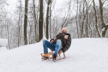 Älterer Mann, der sich an einem kalten Wintertag vergnügt und den Berg hinunterschlittert. Älterer Mann, der seinen Winterurlaub in den Bergen verbringt. Winterliche Landschaft. - HPIF34532