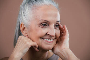 Porträt einer lächelnden älteren Frau in einem Studio. - HPIF34605
