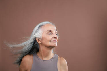 Porträt einer lächelnden älteren Frau in einem Studio. - HPIF34610