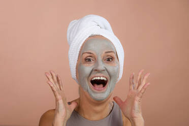 Porträt einer aufgeregten älteren Frau mit einer Gesichtsmaske, einem Konzept für Selbstpflege und Hautroutine. - HPIF34619