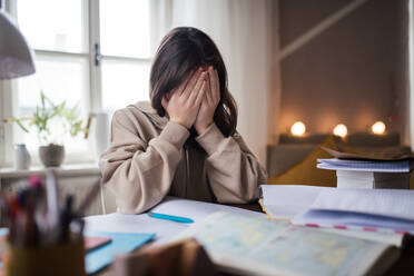 Unhappy girl doing a homework in her room. - HPIF34773