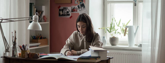 Young teenage girl studying and doing homework in her room. - HPIF34780