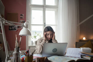 Young teenage girl studying and doing homework in her room. - HPIF34783