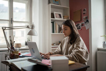 Junges Mädchen im Teenageralter, das in ihrem Zimmer lernt und Hausaufgaben macht. - HPIF34787