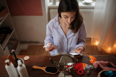 Teenage girl doing her skin care routine and checking her smartphone. - HPIF34804