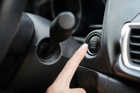 Close up of finger pressing engine start button until engine turns on. A keyless ignition system. - HPIF34860