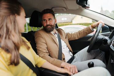 Portrait of young couple holding hands and sitting in their first new car. The newlyweds received a car as a wedding gift. - HPIF34861