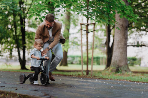 Alleinstehender Vater mit seinem kleinen Sohn, der in einem öffentlichen Park Zeit miteinander verbringt. Berufstätiges Elternteil, das nach der Arbeit Zeit mit seinem Sohn verbringt. - HPIF34878