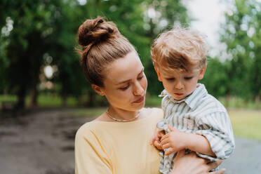 Young mother with little son on a walk after work. Working mother picking up her son from daycare. - HPIF34900