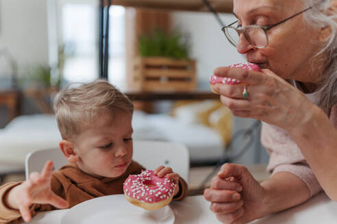 Kleiner Junge isst süßen Snack mit seiner Großmutter. - HPIF34918