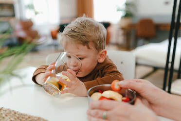 Kleiner Junge trinkt einen Tee und isst eine Kleinigkeit mit seiner Großmutter. - HPIF34924