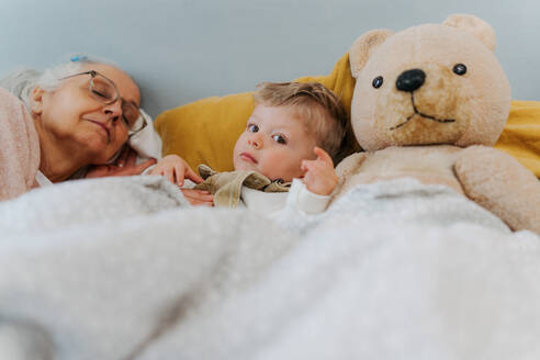 Großmutter liegt mit ihrem Enkel in einem Bett. - HPIF34960