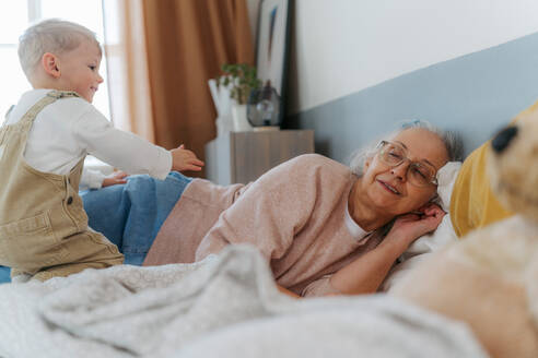 Großmutter liegt mit ihrem Enkel in einem Bett. - HPIF34961