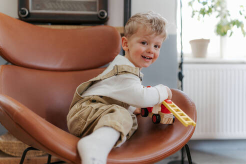 Glücklicher kleiner Junge spielt mit rotem Feuerwehrauto Spielzeug im Wohnzimmer. - HPIF34962