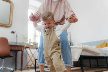 Eine Großmutter bringt ihrem kleinen Enkel zu Hause das Laufen bei. - HPIF35003