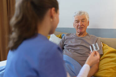 Krankenschwester gibt Tabletten älteren Mann in seiner Wohnung. - HPIF35015