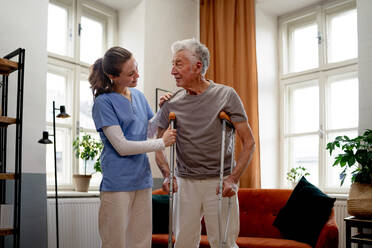 Junge Krankenschwester hilft einem älteren Mann beim Gehen. - HPIF35029