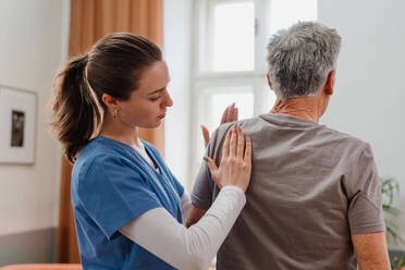 Young nurse doing exercise with senior man in his home. - HPIF35033