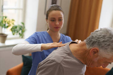 Young nurse doing exercise with senior man in his home. - HPIF35034