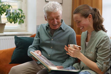 Älterer Mann mit seiner Enkelin, die ein Buch liest. - HPIF35046