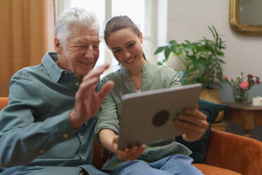 Senior man with his granddaughter using digital tablet together. - HPIF35049