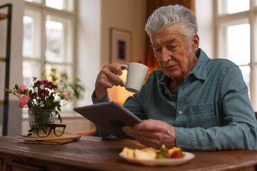 Ein älterer Mann liest etwas auf einem digitalen Tablet. - HPIF35053