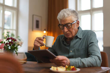 Ein älterer Mann liest etwas auf einem digitalen Tablet. - HPIF35054