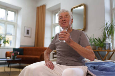 Porträt eines älteren Mannes, der nach der Einnahme von Tabletten Wasser trinkt. Bedeutung der Flüssigkeitszufuhr für ältere Menschen. - HPIF35062