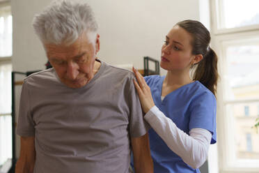 Young nurse doing exercise with senior man in his home. - HPIF35068