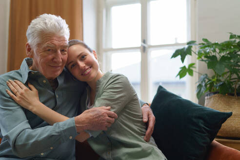 Junge Frau, die ihren Großvater im Heim umarmt. - HPIF35078