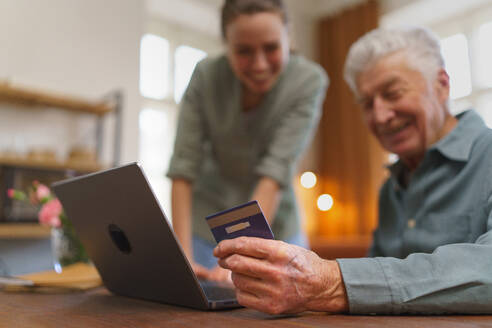 Älterer Mann mit seiner Betreuerin beim Online-Shopping im Notebook. - HPIF35082