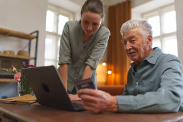Senior man with his caregiver online shopping at notebook. - HPIF35083