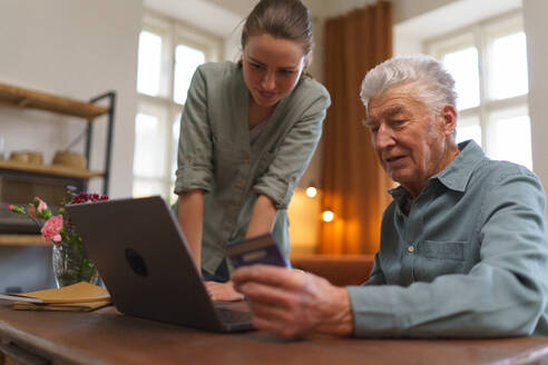 Älterer Mann mit seiner Betreuerin beim Online-Shopping im Notebook. - HPIF35083