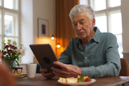 Ein älterer Mann liest etwas auf einem digitalen Tablet. - HPIF35086