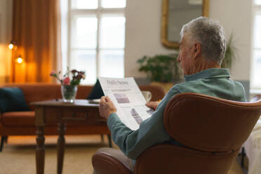Älterer Mann liest Zeitung in der Wohnung. - HPIF35087