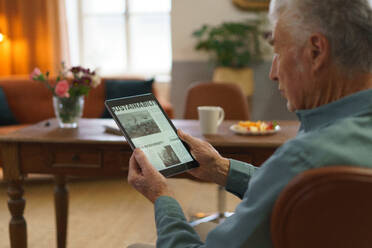 Ein älterer Mann liest Nachrichten auf einem digitalen Tablet. - HPIF35088