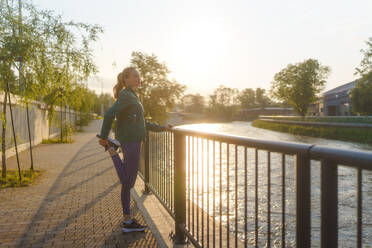 Junge Läuferin dehnt sich vor ihrem morgendlichen Lauf. Fitness-Mädchen in Sportkleidung bereitet sich auf das Abendtraining vor. Outdoor-Workout-Konzept. - HPIF35097