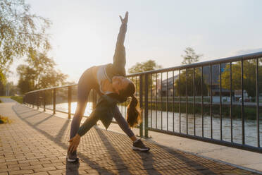 Junge Läuferin dehnt sich vor ihrem morgendlichen Lauf. Fitness-Mädchen in Sportkleidung bereitet sich auf das Abendtraining vor. Outdoor-Workout-Konzept. - HPIF35107