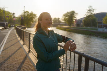 Porträt einer sportlichen Frau, die nach dem Training ihre Leistung auf der Smartwatch überprüft. Die Frau benutzt die Smartwatch, um eine Textnachricht zu senden und zu telefonieren. - HPIF35109