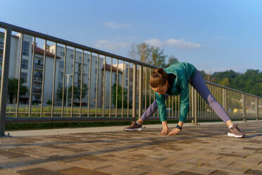 Junge Läuferin dehnt sich vor ihrem morgendlichen Lauf in der Stadt. Fitness-Mädchen in Sportkleidung bereitet sich auf das Abendtraining vor. Outdoor-Workout-Konzept. - HPIF35120