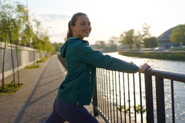 Junge Läuferin dehnt sich vor ihrem morgendlichen Lauf in der Stadt. Fitness-Mädchen in Sportkleidung bereitet sich auf das Abendtraining vor. Outdoor-Workout-Konzept. - HPIF35125