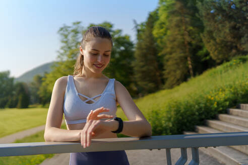 Potrait einer sportlichen Frau, die nach dem Training ihre Leistung auf der Smartwatch überprüft. Die Frau benutzt die Smartwatch, um Textnachrichten zu senden und zu telefonieren. - HPIF35154