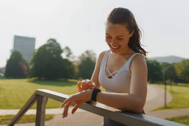 Sportliche Frau, die nach dem Training ihre Leistung auf der Smartwatch überprüft. Frau, die eine Smartwatch zum Senden von Textnachrichten und Anrufen verwendet. - HPIF35155