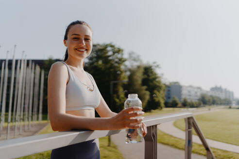 Porträt einer sportlichen Frau, die nach dem Training Wasser aus einer Flasche trinkt. Wichtig ist die Flüssigkeitszufuhr während des Trainings. - HPIF35156