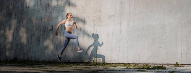 Hübsche Sportlerin in Sportkleidung beim Training in der Stadt mit Kopierraum. - HPIF35182