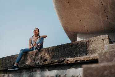 Young fitness woman resting after workout session in the city. Beautiful sporty woman enjoying sunrise after morning excercise. - HPIF35202