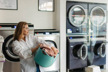 Young woman waiting in the laundry room. - HPIF35267