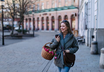 Young woman in a city with a basket full of flowers. - HPIF35271